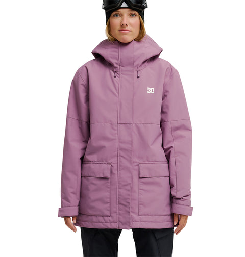 A person wearing a light purple DC Shoes Cruiser Jacket—a stylish waterproof jacket designed for optimal snow performance—paired with black pants and a black helmet, stands facing forward against a plain white background.