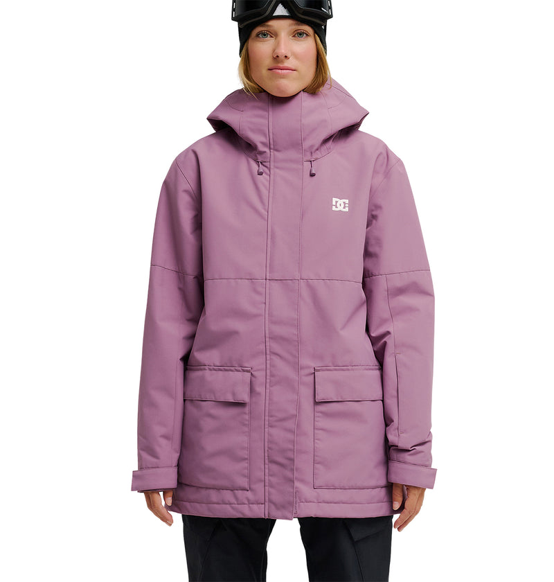 A person wearing a light purple DC Shoes Cruiser Jacket—a stylish waterproof jacket designed for optimal snow performance—paired with black pants and a black helmet, stands facing forward against a plain white background.