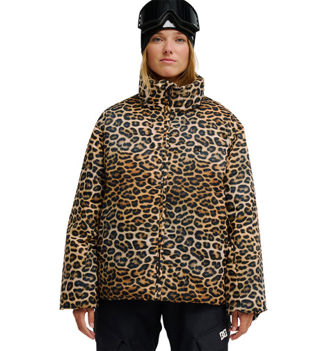 Clad in the DC Shoes Aura Puffer Jacket—a leopard-print, waterproof outer layer—paired with black snow pants and black ski goggles, this look merges bold style with breathable protection for peak snow performance against a white backdrop.