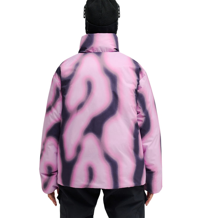 A person wearing a black beanie and the DC Shoes Aura Puffer Jacket, featuring a pink and black abstract pattern, is photographed from behind against a white background—showcasing both breathable protection and style.