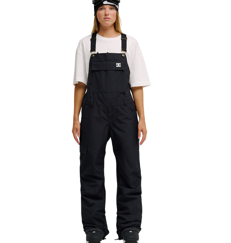 A person wearing DC Shoes’ Valiant Bib Pants, styled with a black beanie and white T-shirt, stands facing forward against a white background—ready for snow performance with the bib’s breathable protection.