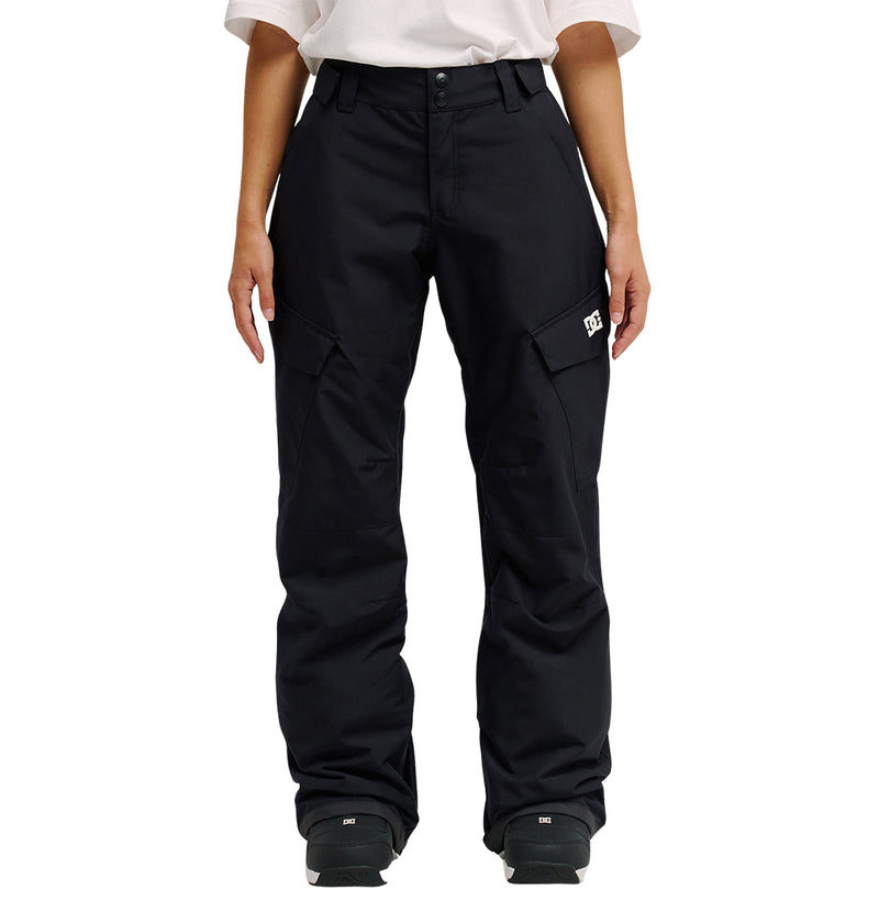 A person is shown from the waist down, wearing DC Shoes’ Nonchalant Pant in black with a white shirt. The pants are loose-fitting and insulated, featuring flap pockets and a small white DC Shoes logo on the left thigh for added style and dependable snow performance. Their arms rest relaxed at their sides.