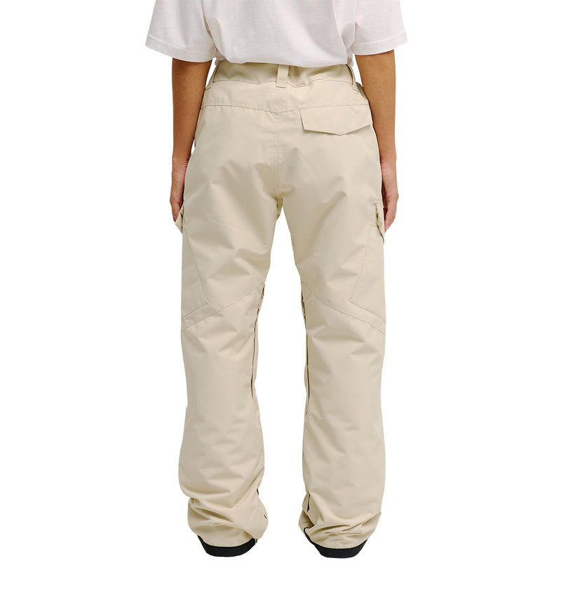 A person stands facing away from the camera, showing the back view of the DC Shoes Nonchalant Pants in beige, paired with a white t-shirt.
