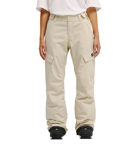 A person wearing the DC Shoes Nonchalant Pants—loose, beige insulated cargo pants with large side pockets, belt loops, and enhanced waterproofing for improved snow performance—along with a white t-shirt and black shoes stands facing forward.