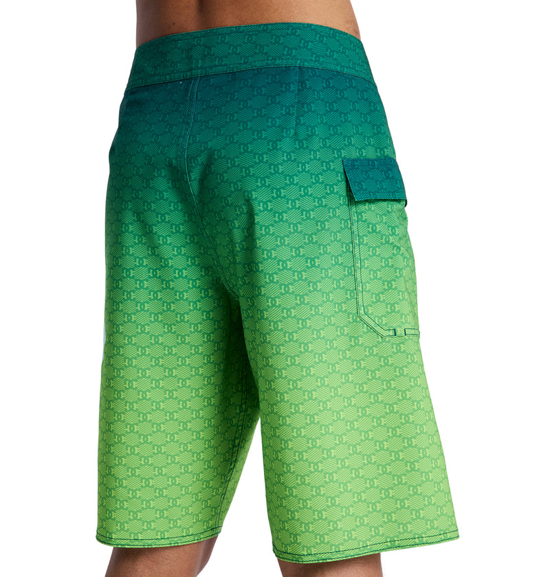 A person shown from the back wearing Reebok Lanai 21 board shorts featuring a green and blue gradient, subtle repeating pattern, and a right-side flap pocket.