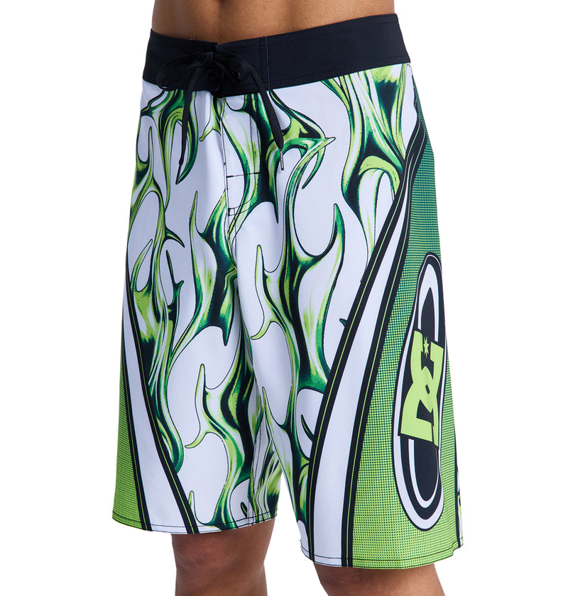 A person wearing Reebok Sylem 21 board shorts in green, black, and white with flame graphics. Only the lower torso and upper legs are visible.