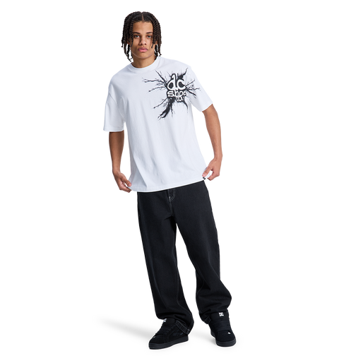 A person with braided hair wears a white graphic tee, black DC Shoes sneakers, and the Men's Baggy Denim Pant by DC Shoes, all set against a plain white background.