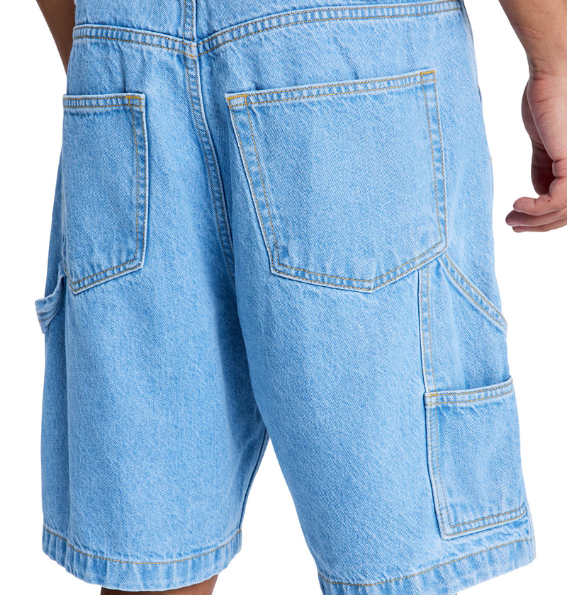 A close-up shows the back of a person wearing Reebok Baggy Denim Carpenter Shorts in light blue, featuring large pockets and visible stitching. The person's right arm is partially visible.
