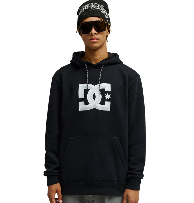 A person wearing the DC Shoes Snowstar hoodie—a black sweatshirt with a large white DC logo—paired with sunglasses and a black beanie, stands facing forward against a plain white background, highlighting the Snowstar’s weather protection and comfortable fit ideal for snow-day performance.