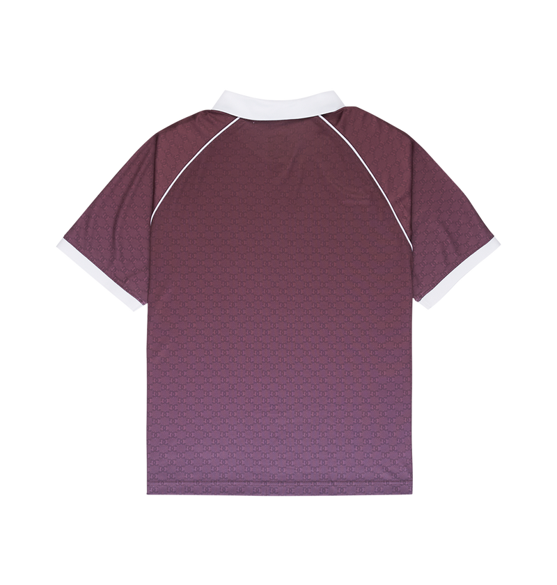 A person with short, braided hair is seen from behind in the DC Shoes Men's DC Soccer Top—a maroon skate-inspired jersey with a white collar and sleeve trim—paired with light blue jeans against a plain white background.
