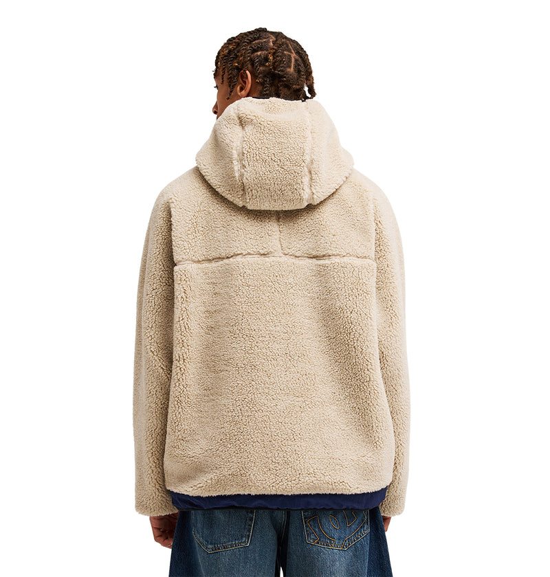 A person with short, braided hair is seen from the back against a white background, wearing blue jeans and the beige Coldstag Sherpa Reversible hooded fleece jacket by DC Shoes. The fleece construction of this jacket delivers cold-weather comfort for any outing.