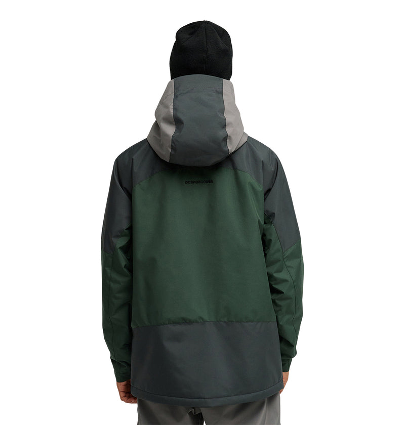 A person wearing the DC Shoes Coldsmoke Jacket 10K—a green and gray snow performance jacket with breathable protection—and a black beanie stands facing away from the camera against a plain white background.