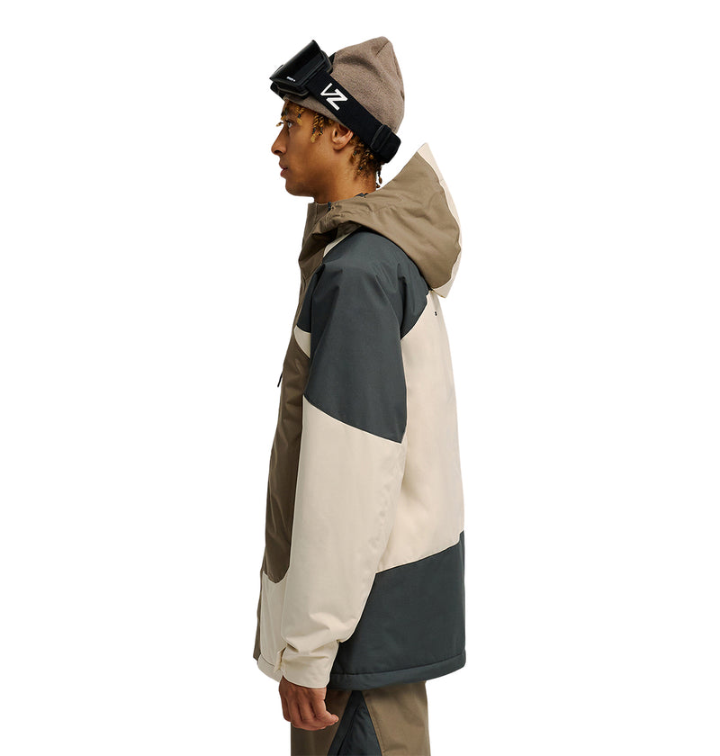 Wearing the DC Shoes Coldsmoke Jacket 10K in tan and dark gray, along with matching pants, a brown beanie, and goggles, a person stands in profile facing left against a white background. This outfit delivers breathable waterproof protection for optimal snow performance.