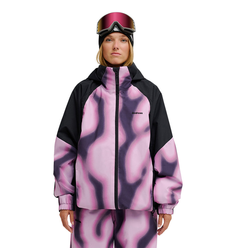 A person wearing the DC Shoes Trackstar Jacket 10K—a pink and black patterned ski jacket and pants offering breathable protection—along with a black hood and ski goggles, stands against a white background.