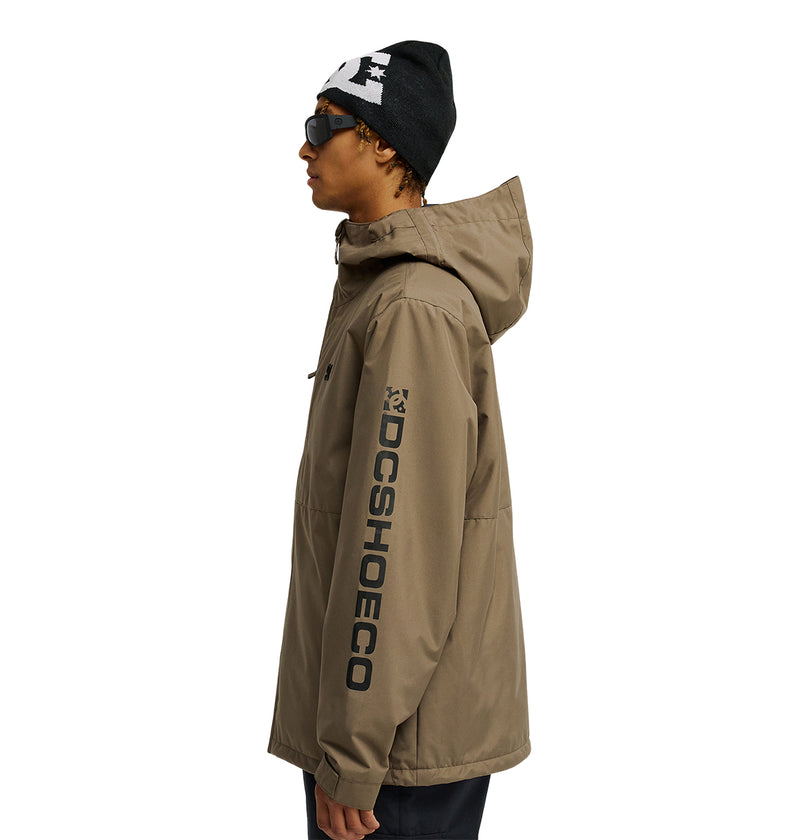 A person in profile wearing the DC Shoes Basis Jacket 10K in tan—with DCSHOECO text on the sleeve—paired with a black beanie featuring a white logo and dark sunglasses against a plain white background, delivering breathable protection in style.