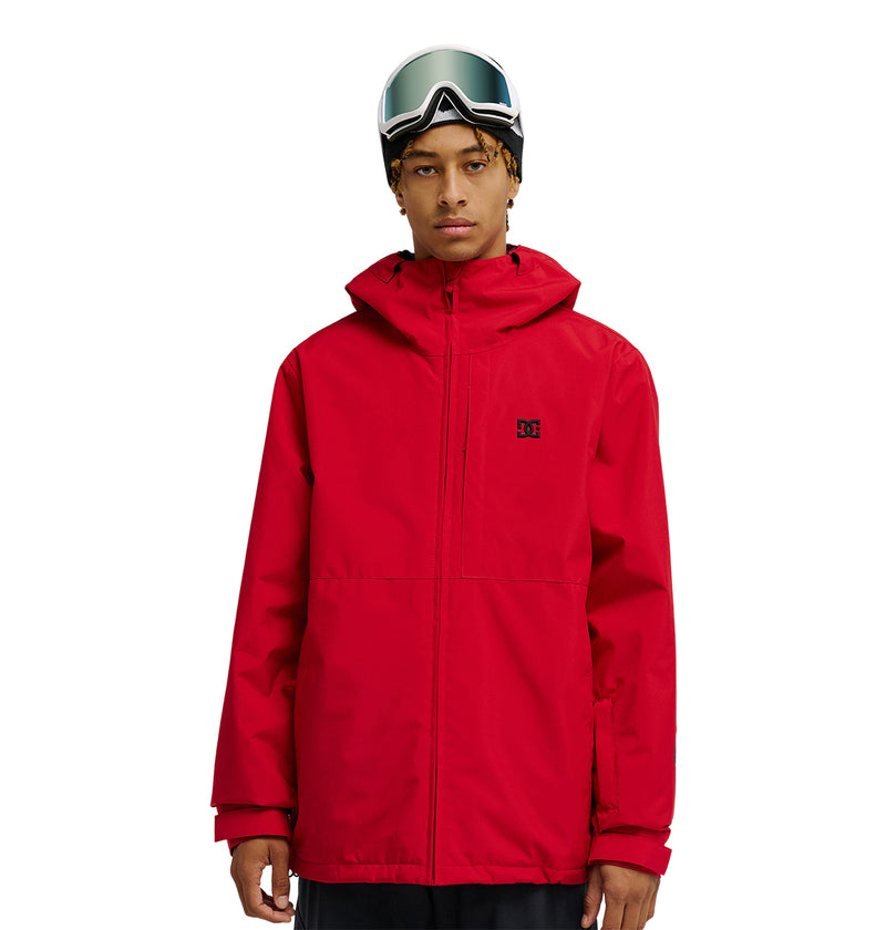 A person wearing the DC Shoes Basis Jacket 10K in red and ski goggles stands facing forward against a white background.