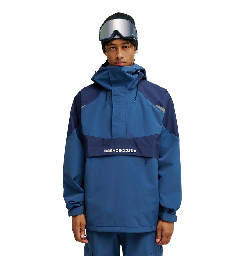 A person wearing the DC Shoes Mountain Lab Anorak 10K snowboard jacket, matching pants, and ski goggles stands facing forward with a neutral expression. The jacket offers breathable protection for optimal snow performance.