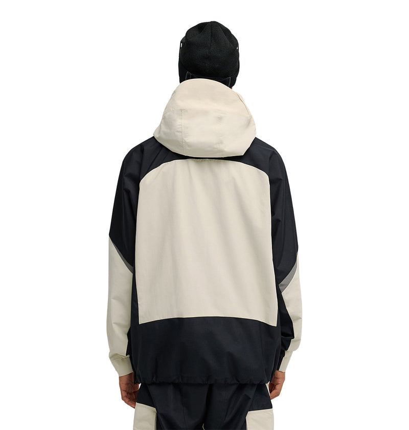 A person is shown from the back against a white background, wearing the DC Shoes Mountain Lab Anorak 10K in black and beige with the hood up, paired with a black hat.