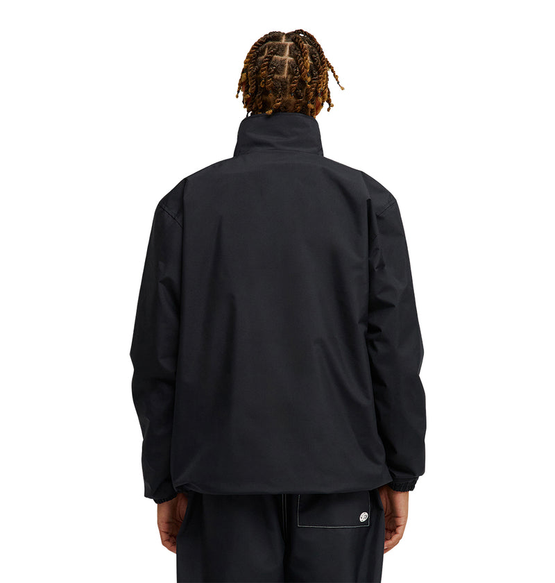 A person with short, twisted hair is shown from behind, wearing the DC Shoes Park Reversible Anorak and black pants against a plain white background. The jacket has a high collar, loose fit, and provides dependable waterproofing for excellent snow performance. Their hands rest relaxed at their sides.