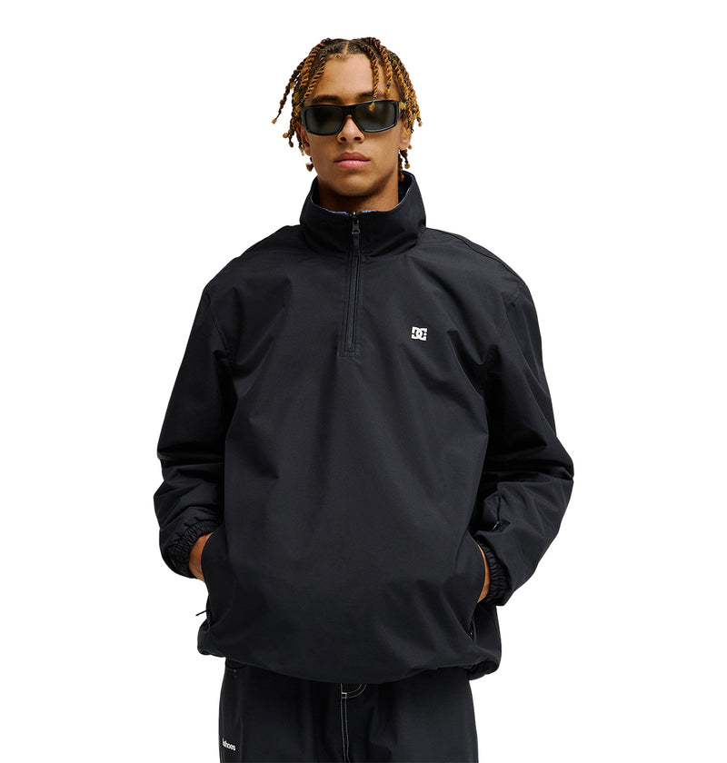 A person wearing the DC Shoes Park Reversible Anorak in black, with hands in pockets and dark sunglasses, stands against a plain white background.