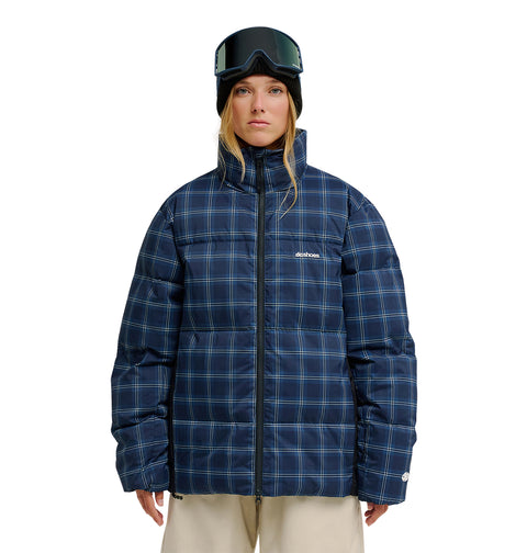 A woman wearing a black beanie, ski goggles, and the DC Shoes Trackstar Puffer 10K blue plaid insulated winter jacket stands against a white background.