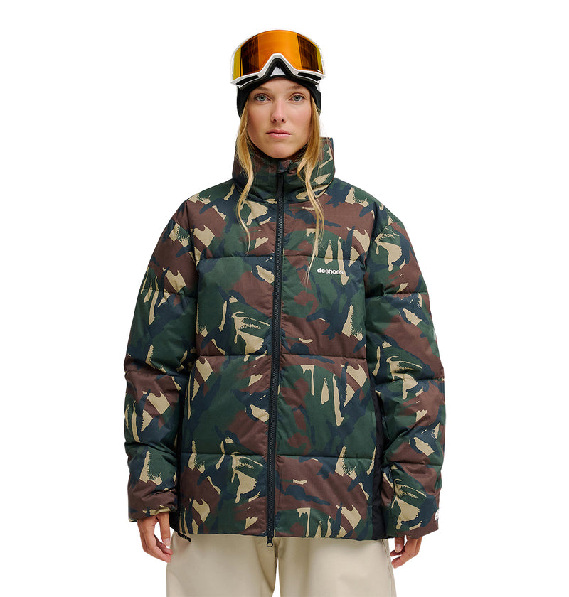 A woman stands facing forward with her hands by her sides against a plain white background, wearing DC Shoes’ Trackstar Puffer 10K ski jacket and ski goggles.