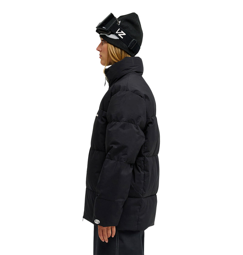 Wearing the DC Shoes Trackstar Puffer 10K jacket, along with black pants, a black beanie, and ski goggles, a person stands in profile against a white background—ready for peak snow performance with breathable protection.