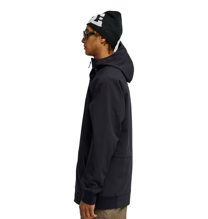 A person in the DC Shoes Spectrum Softshell Jacket, featuring a hoodie, sunglasses, and a black beanie, stands in profile against a white background, showcasing stylish and breathable protection.