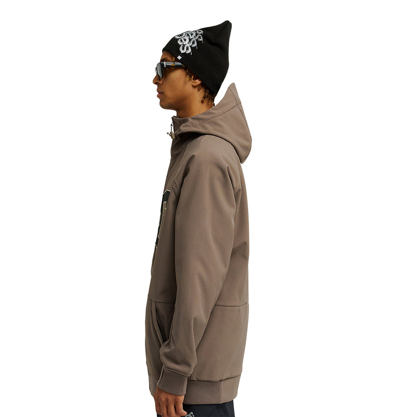 Wearing the DC Shoes Spectrum Softshell Jacket in taupe, a person in profile stands against a white background, accessorized with sunglasses and a black beanie featuring a white design.