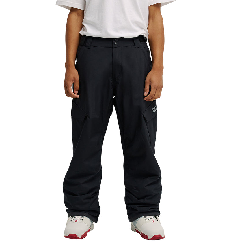 A person wearing a white t-shirt, DC Shoes Banshee Pants in black, and white sneakers with red accents stands facing forward against a plain background.
