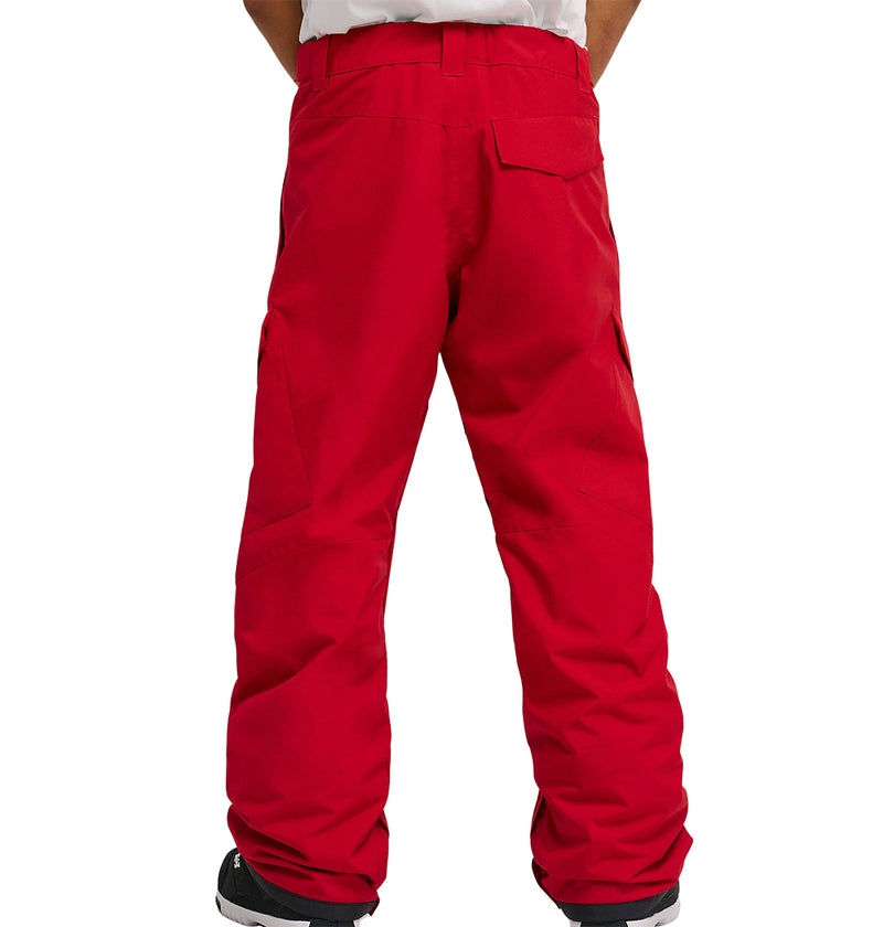 A person stands with their back to the camera, wearing DC Shoes Banshee Pants in bright red, featuring visible pockets and stitching details, paired with black shoes with white soles.