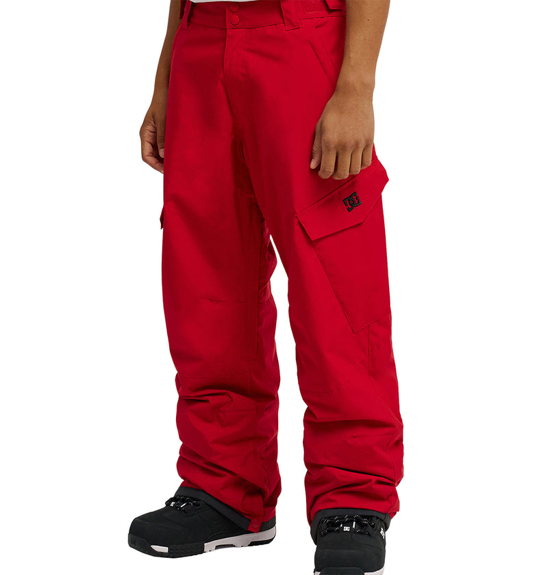 A person wearing DC Shoes Banshee Pants in bright red and black boots, standing against a plain white background. Only the lower half of the body is visible.