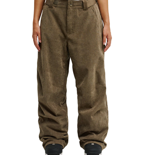 A person is wearing DC Shoes’ Snow Carpenter Pant 10K in loose-fitting brown corduroy, paired with black shoes. Shown from waist to feet against a white background, their hands rest at their sides. The pants feature a textured, ribbed design that delivers comfort and weather protection.