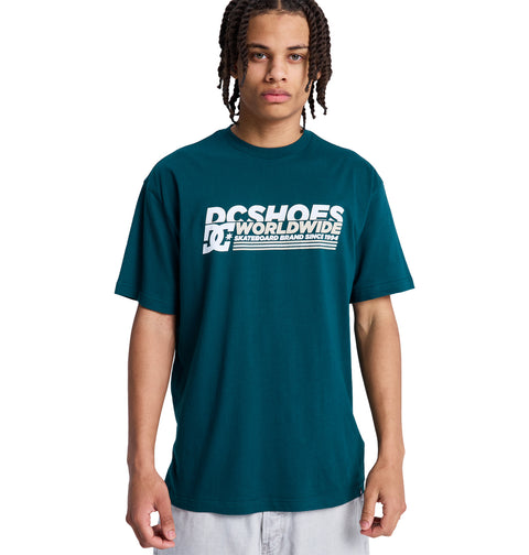A young person with braided hair wears a teal Reebok Queltra Lhss t-shirt and stands facing forward against a plain white background.