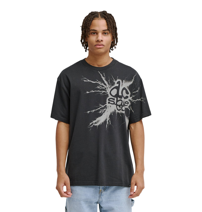 A young man with braided hair wears the Reebok Strike Twice Hss—a loose black t-shirt with a bold, abstract white graphic and text—standing facing forward, arms relaxed at his sides against a plain white background.