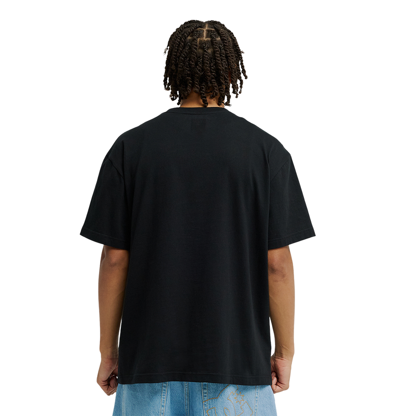 A person with short twists is shown from the back, wearing the Men’s DC Strass Star Tee by DC Shoes in soft cotton, paired with light blue jeans against a white background.