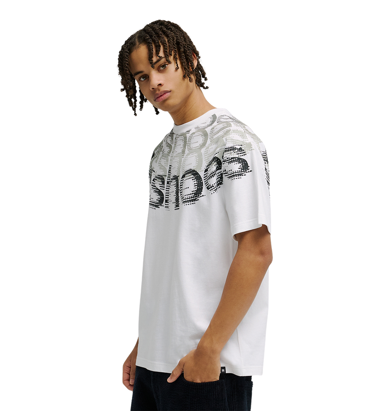 A young person with medium-length braids wears the Men’s DC Omega 2 Tee by DC Shoes—a loose, white skate t-shirt crafted from soft cotton and featuring layered, distorted black and gray text across the chest and shoulders—standing against a plain white background.