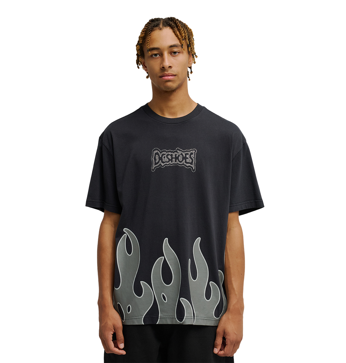 A young man with short braids wears the Men's DC Burning Diamonds Tee from DC Shoes—a black graphic skate t-shirt featuring the iconic Dogshoes logo on the chest and gray flame graphics at the hem, inspired by burning diamonds artwork. He stands out against a plain, light background, looking directly at the camera.