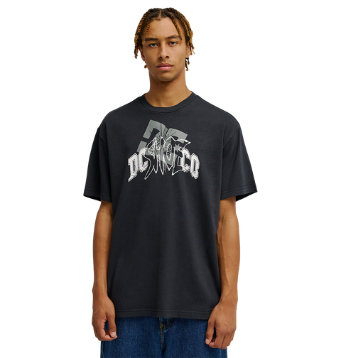 A person with braided hair wears the Men's DC Speratic Tee by DC Shoes—a relaxed fit black graphic skate t-shirt with a bold white logo—paired with blue jeans, standing against a plain white background.