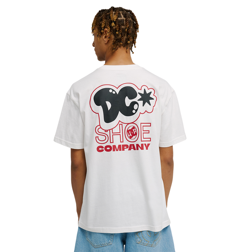 A person is seen from behind wearing the Men's DC Side Flame Tee by DC Shoes—a relaxed fit white T-shirt featuring a bold black and red DC Shoe Company logo on the back—paired with light blue jeans.