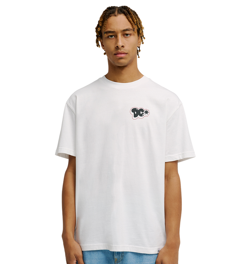 A person with short, light brown braids wears the Men's DC Side Flame Tee from DC Shoes, a relaxed fit white skate shirt featuring a small black and white graphic on the left chest, standing against a plain white background.
