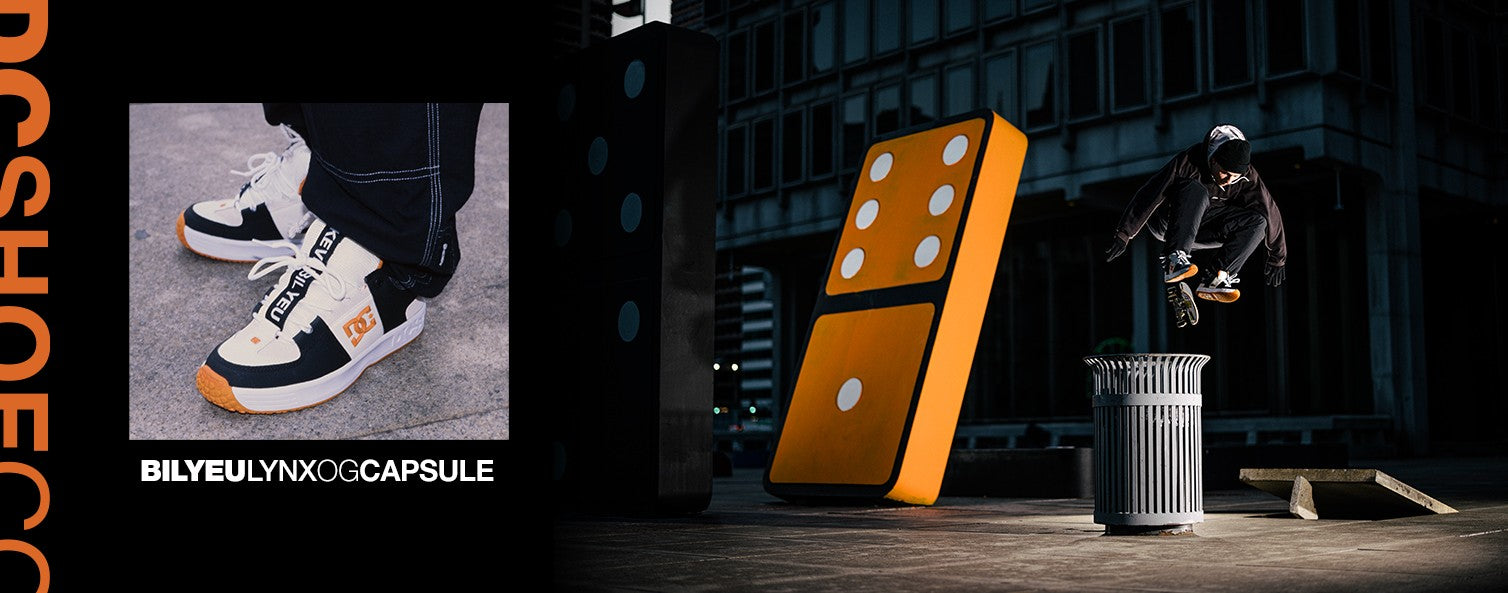 A skateboarder in black clothing and orange-accented sneakers performs a trick over a trash can near a giant domino sculpture in an urban setting. Close-up of the sneakers is shown on the left, labeled BILLYEULYNXOGCAPSULE.