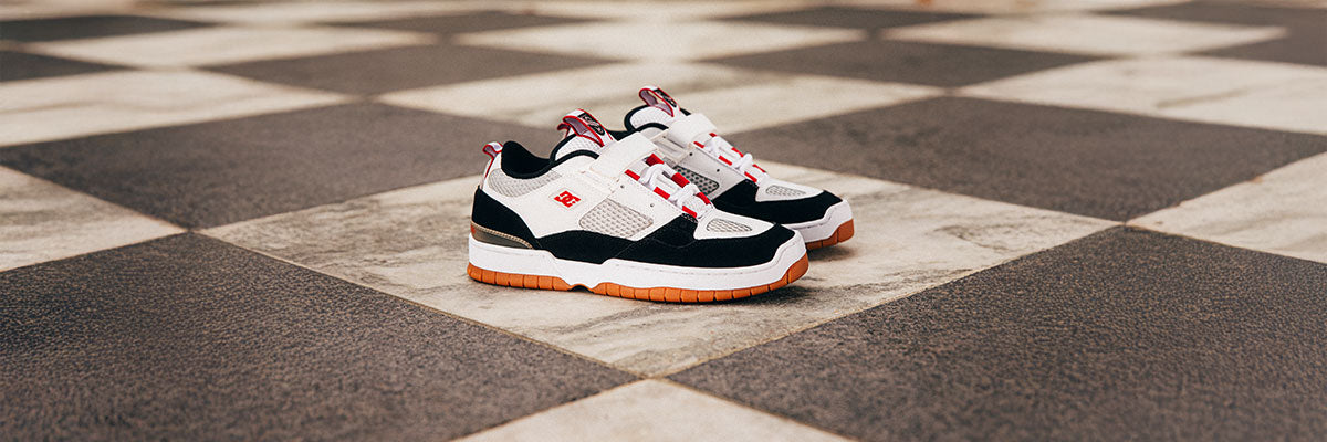 Pair of black, white, and red sneakers on a checkered floor.