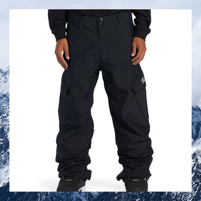 Black snow pants worn by a person with a snowy mountain background