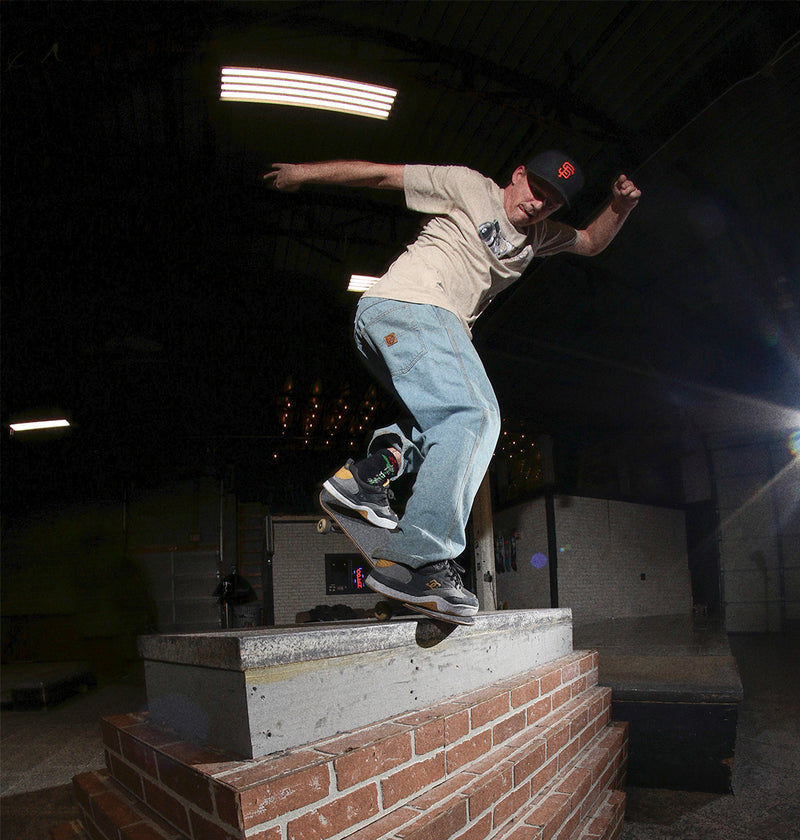 Person skateboarding on a concrete ledge with a dark indoor setting