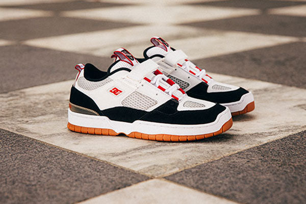 Pair of black, white, and red sneakers on a checkered pavement.