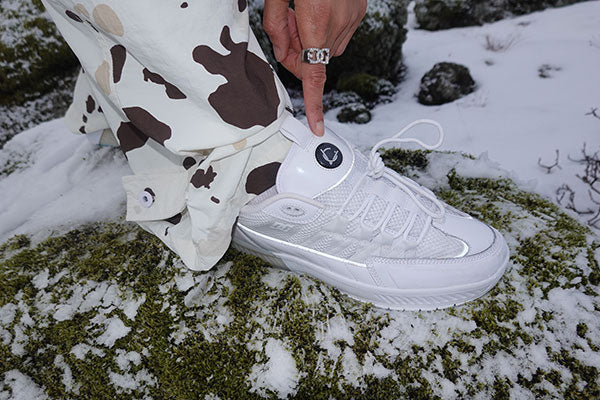 White sneaker with a brand logo on a snowy ground
