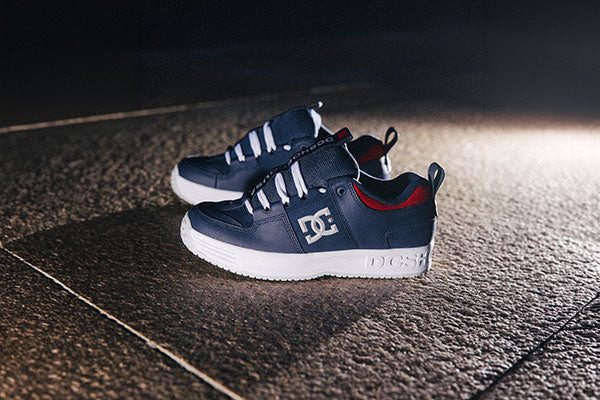 Pair of navy blue sneakers with white soles on a dark textured surface