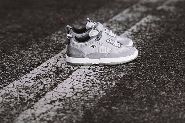 Gray and white sneakers on a cracked asphalt surface