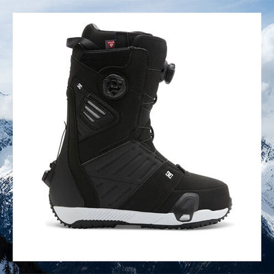 Black snowboard boot with white sole on a snowy background
